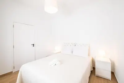 a white bedroom with a white bed with white sheets at SERAFIM BEACH APARTMENT - Heart of the Old Town in Albufeira