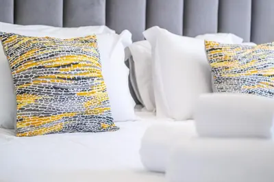 a white bed with white pillows and a couch at Apartamento Casa Vela in Albufeira