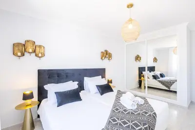 two beds in a white bedroom with a mirror at Apartamento Casa Vela in Albufeira