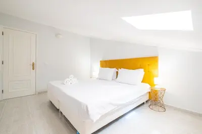 a white bedroom with a large bed with white sheets at Apartamento Casa Vela in Albufeira