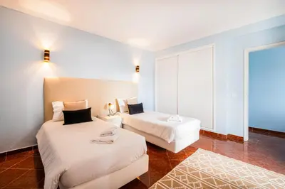 two beds in a room with a large window at Villa Melissa in Albufeira