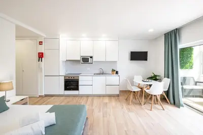 a kitchen with white cabinets and a table and chairs at Studio Guerreiro in Albufeira
