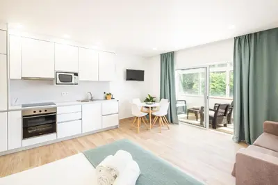 a kitchen and living room with white cabinets and a table at Studio Guerreiro in Albufeira