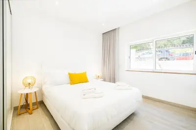 a white bedroom with a white bed and a window at Guerreiros Lovely Stay in Albufeira