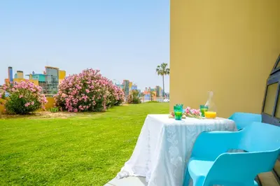 a table with two blue chairs and a green yard at Anabella Guest House in Albufeira