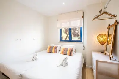 a white bedroom with two beds and a window at Anabella Guest House in Albufeira