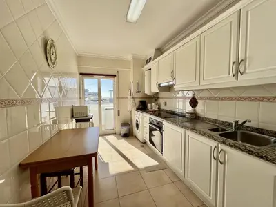 a kitchen with white cabinets and a sink and a table at Albufeira Vintage Apartment 1 With Pool by Homing in Albufeira