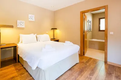a bedroom with a large white bed and a bathroom at Casa Picota in Boliqueime