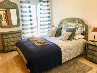 a bedroom with a bed with a blue blanket and a mirror at Charming 3 bed apartment @ Al-Sakia Village in Quarteira