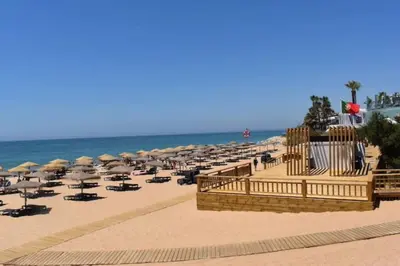 a beach with many umbrellas and chairs and the ocean at Charming 5 bed Private Villa - Quarteira in Quarteira