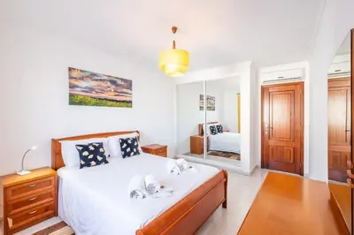 a bedroom with a bed with white sheets and a mirror at Apartment Arrifes in Albufeira