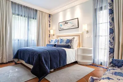 a bedroom with a blue and white bed and windows at Pine Cliffs Suites in Albufeira