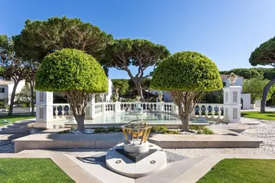 a garden with trees and a trophy in the middle at Pine Cliffs Suites in Albufeira