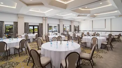 a banquet room with white tables and chairs at Pine Cliffs Suites in Albufeira