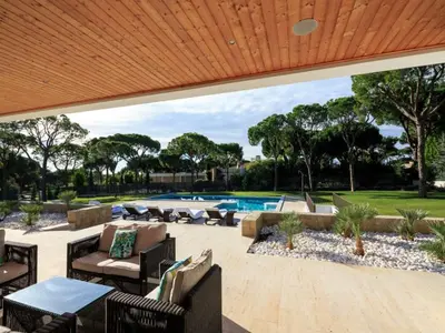 an outdoor patio with chairs and a swimming pool at Contemporary Vilamoura Villa Stunning Open Plan Design Villa Azure Elegance in Quarteira