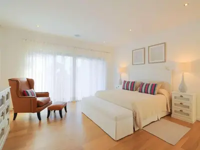 a white bedroom with a bed and a chair at Contemporary Vilamoura Villa Stunning Open Plan Design Villa Azure Elegance in Quarteira
