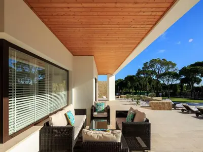 an outdoor patio with wicker furniture and a wooden ceiling at Contemporary Vilamoura Villa Stunning Open Plan Design Villa Azure Elegance in Quarteira