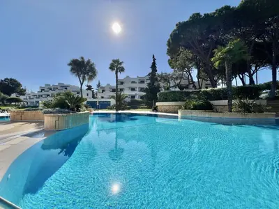 a large blue swimming pool with palm trees and condos at Albufeira Balaia Golf Vilage 4 With Pool by Homing in Albufeira