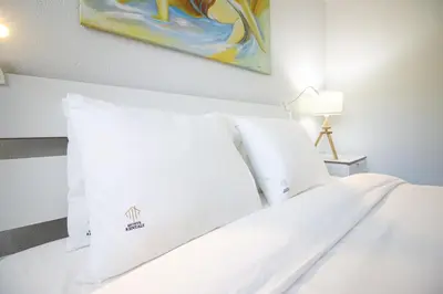 a white bed with white pillows and a painting on the wall at Lovely 3BD 150m Beach Ocean View AC Wi-Fi Balcony in Albufeira