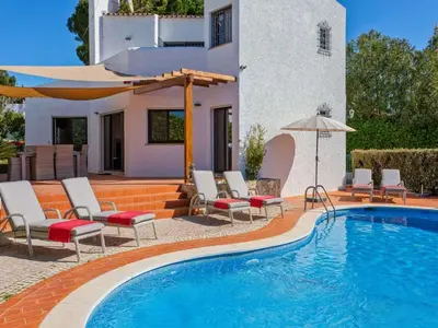 a pool with chairs and an umbrella next to a house at Charming Vilamoura Villa Short Walk To Marina Villa O Clube 3 Bedrooms in Quarteira