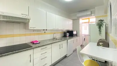 a white kitchen with a sink and a refrigerator at Quarteira Frente Praia II by HomeSlow Rentals in Quarteira