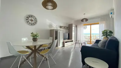 a kitchen and living room with a table and chairs at Quarteira Frente Praia II by HomeSlow Rentals in Quarteira