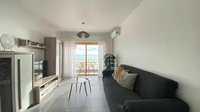 a living room with a couch and a view of the ocean at Quarteira Frente Praia II by HomeSlow Rentals in Quarteira