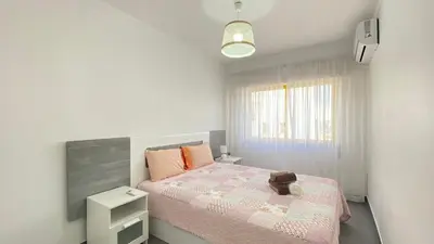 a small bedroom with a pink bed and a window at Quarteira Frente Praia II by HomeSlow Rentals in Quarteira