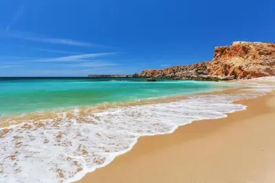 a beach with blue water and a rocky coastline at Villa Gemini in Guia