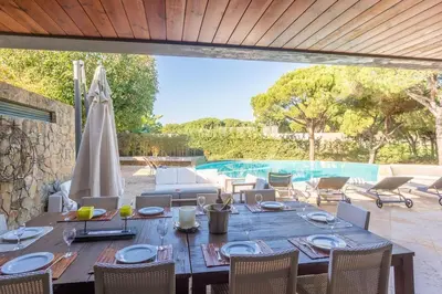 a wooden table with chairs and a pool at Villa Adelaide in Quarteira