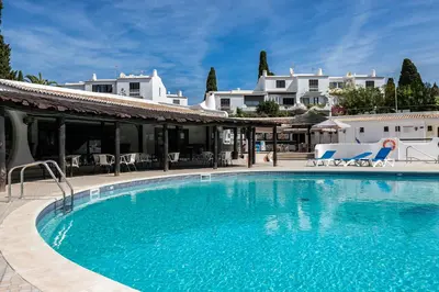 a large blue swimming pool with chairs and buildings at Apartment in São Rafael Albufeira Beach Resort in Albufeira