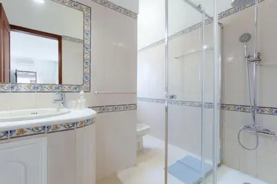 a bathroom with a shower and a sink and a mirror at VILLA ROSADO - Moradia para 6 com AC, jardim a 5 min do centro de Albufeira in Albufeira