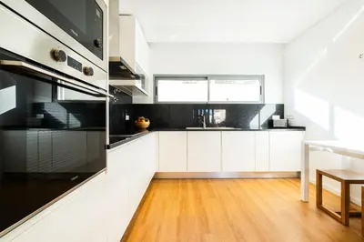 a kitchen with white cabinets and black appliances at Townhouse Varadero by Algarve Vacation in Albufeira