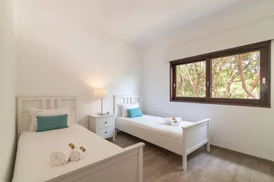 a white bedroom with two beds and a window at Vilamoura M.M. Sunrise T2 in Vilamoura