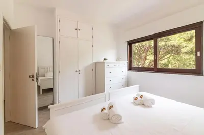 a white bedroom with a bed with two pairs of slippers at Vilamoura M.M. Sunrise T2 in Vilamoura