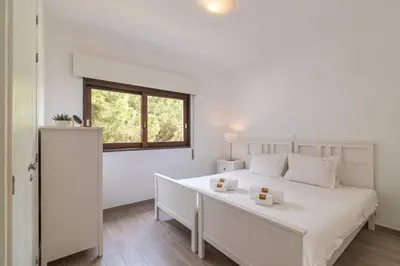 a white bedroom with a large white bed and a window at Vilamoura M.M. Sunrise T2 in Vilamoura