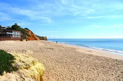 a sandy beach with a building and the ocean at Balaia apartment at Albufeira in Albufeira