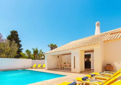 a villa with a swimming pool and yellow chairs at Villa Las Palmas by Algarve Vacation in Albufeira
