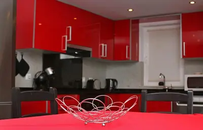 a red kitchen with a red table with a bowl on it at Geneve Old Town Apartment in Albufeira