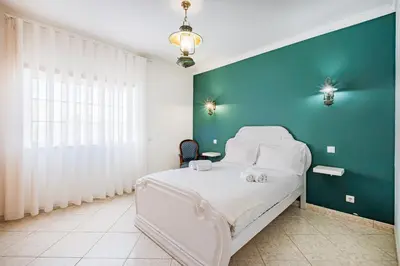 a bedroom with a bed with a blue wall at VILLA LINDA Palace in Guia