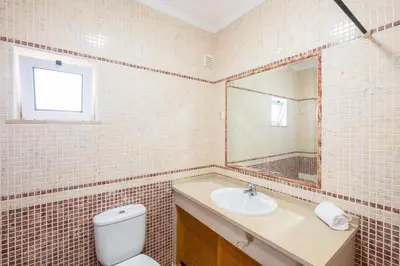 a bathroom with a toilet and a sink and a mirror at Milene Guest House in Albufeira