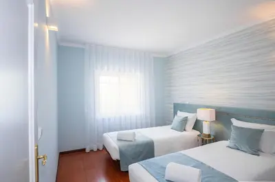 two beds in a room with white walls and wood floors at London Old Town Apartment in Albufeira