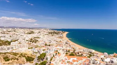 a balcony with chairs and tables and a building at London Old Town Apartment in Albufeira
