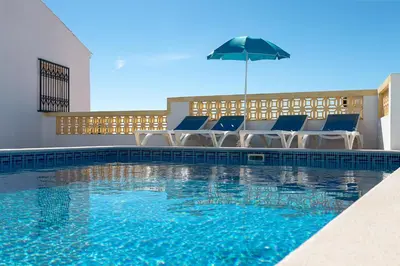 a swimming pool with chairs and an umbrella at Albufeira Marina Villa by Umbral in Albufeira