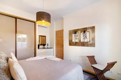a bedroom with a bed and two chairs in it at Apartamento da Ourada Marina luz in Albufeira