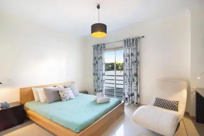 a bedroom with a bed and a chair at Apartamento da Ourada Marina luz in Albufeira