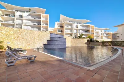 a swimming pool in front of some apartment buildings at Apartamento da Ourada Marina luz in Albufeira