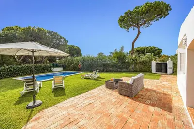 a patio with an umbrella and chairs and a pool at Villa Balaia by Villa Plus in Olhos de Água