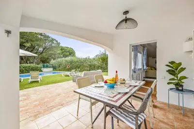 a dining room with a table and chairs and a pool at Villa Balaia by Villa Plus in Olhos de Água