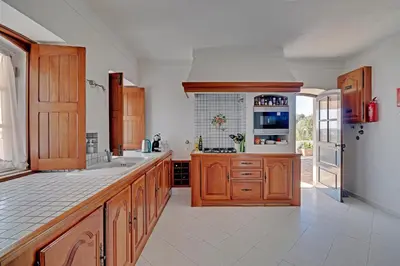 a large kitchen with wooden cabinets and a refrigerator at Casal dos Machados - Vista Mar in Benfarras